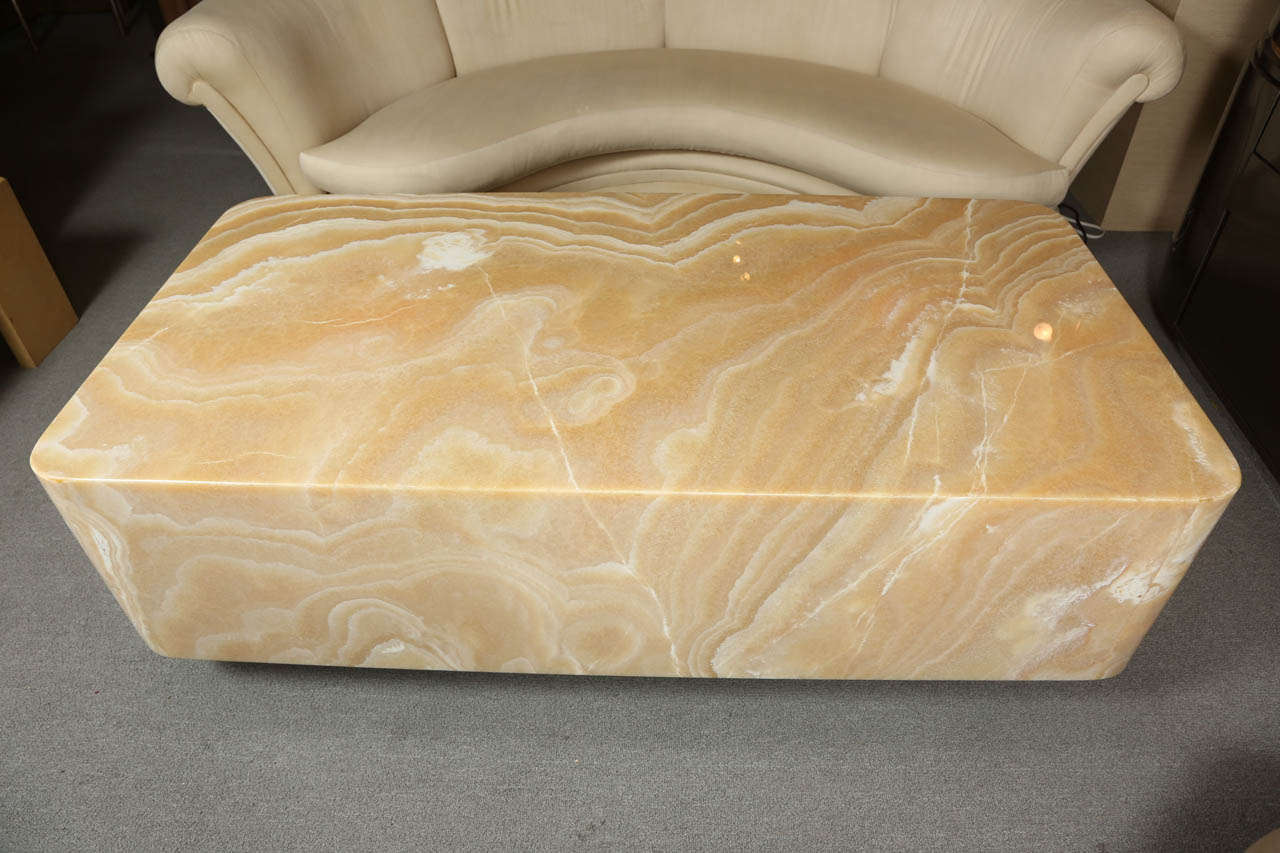 Fabulous onyx coffee table designed by Steve Chase.  The top and sides are solid slabs of onyx. The curved corners are pieced.   They have been matched for veining so that the table appears to be carved from one solid block of onyx.
The table sits