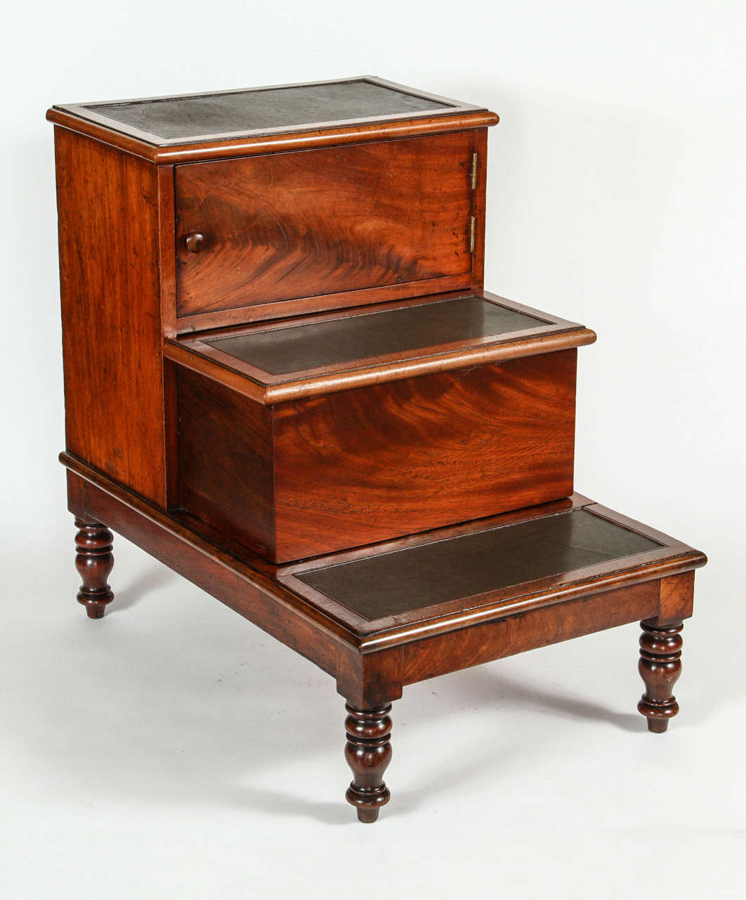 A Georgian Mahogany Bed Step with turned legs and a concealed drawer/shelf on the top step and the second step slides out for a chamber pot (not included), 19th c. with new leather treads.