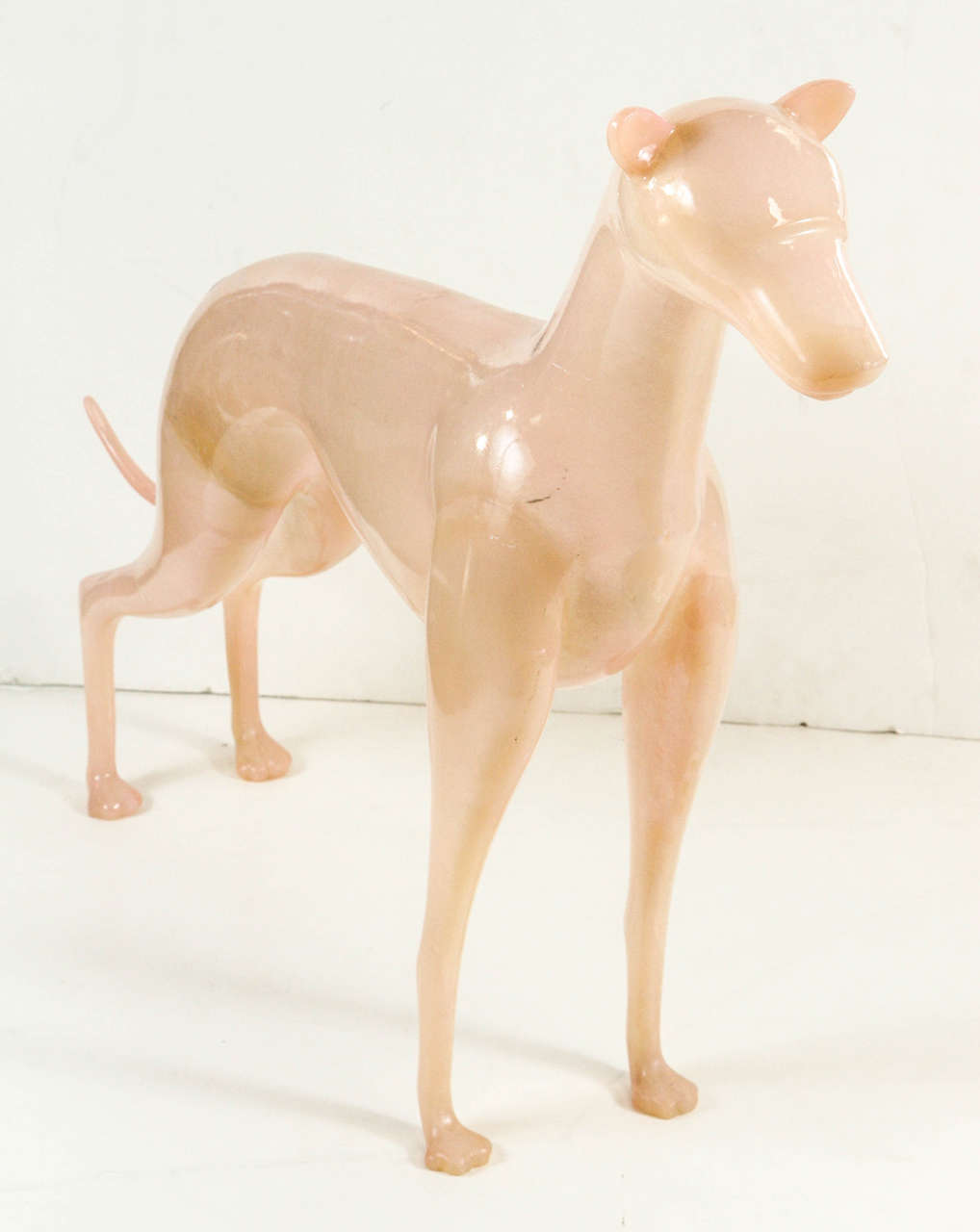 Vintage sculpture of a standing whippet dog cast from a light pink resin material.