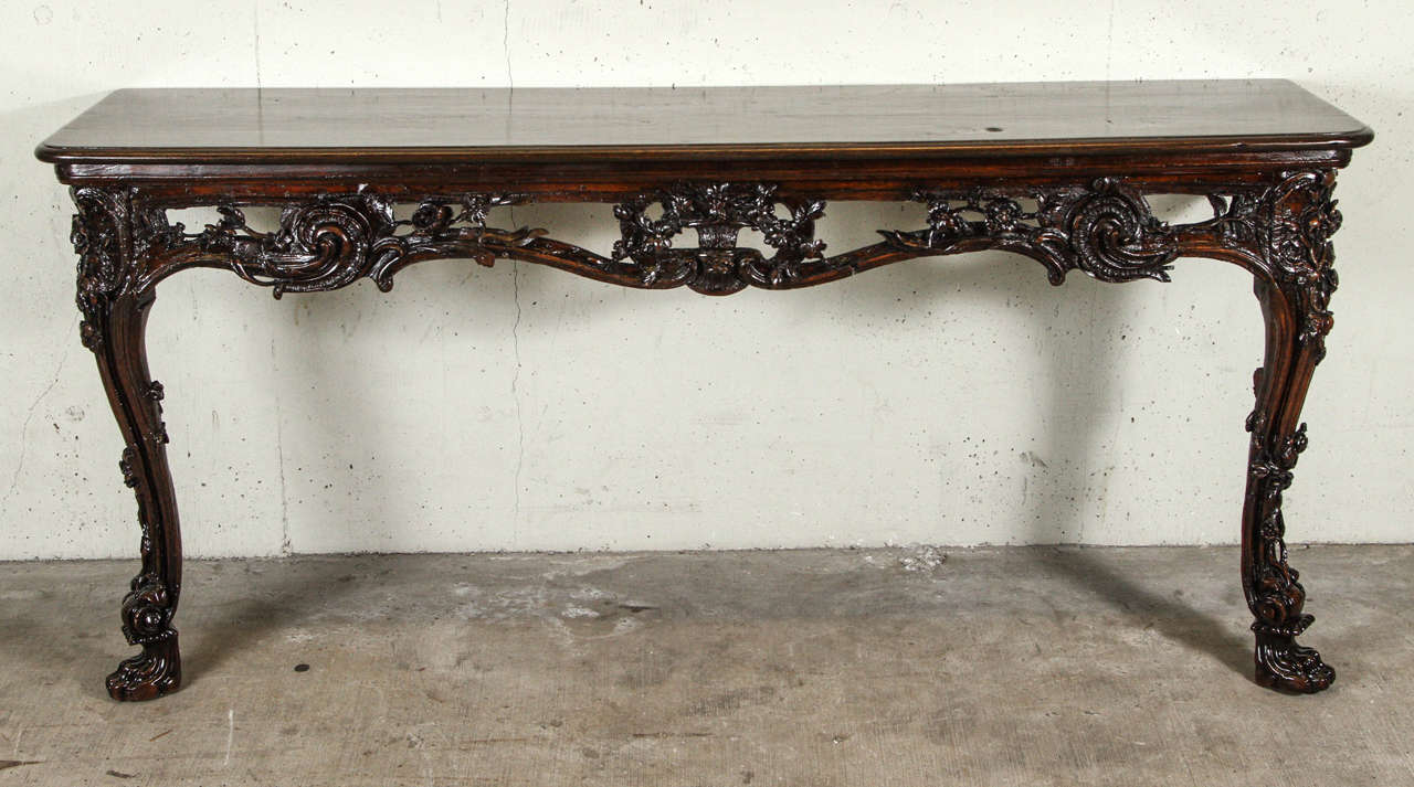 Console table of walnut with carved wood apron and legs. This table has two front legs and back gets bolted to the wall. This piece has newly been refinished.