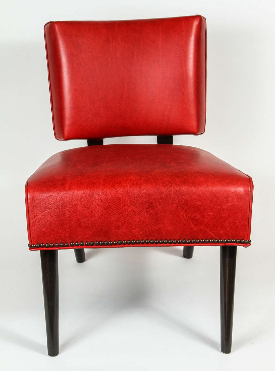 Midcentury chair with newly refinished wood and newly upholstered in red leather with nailhead trim.