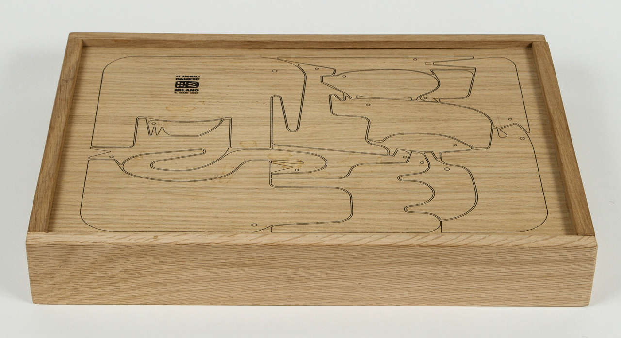 Un délicieux puzzle, conçu par l'éminent designer italien pour Danese Milano en 1957, composé de seize animaux en chêne immédiatement reconnaissables, nichés dans une boîte en chêne avec un couvercle coulissant. L'épaisseur du bois permet à chaque