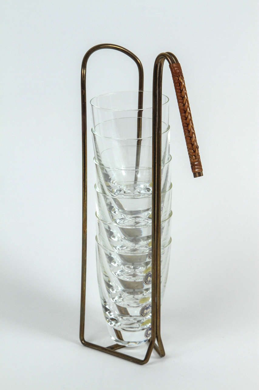 A typically ingenious bar accessory, formed from bent brass rod with a cane wrapped handle. The original glasses are long gone, but this unused set of blown crystal cordials, designed by Per Lütken for Holmegaard, Denmark (circa 1960s), fits very