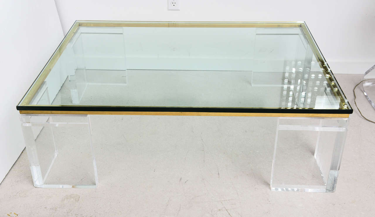 Signed coffee table made by Lion in Frost. Table is composed of three separate components, which include the four Lucite legs, a single brass frame that sits under the glass tabletop.