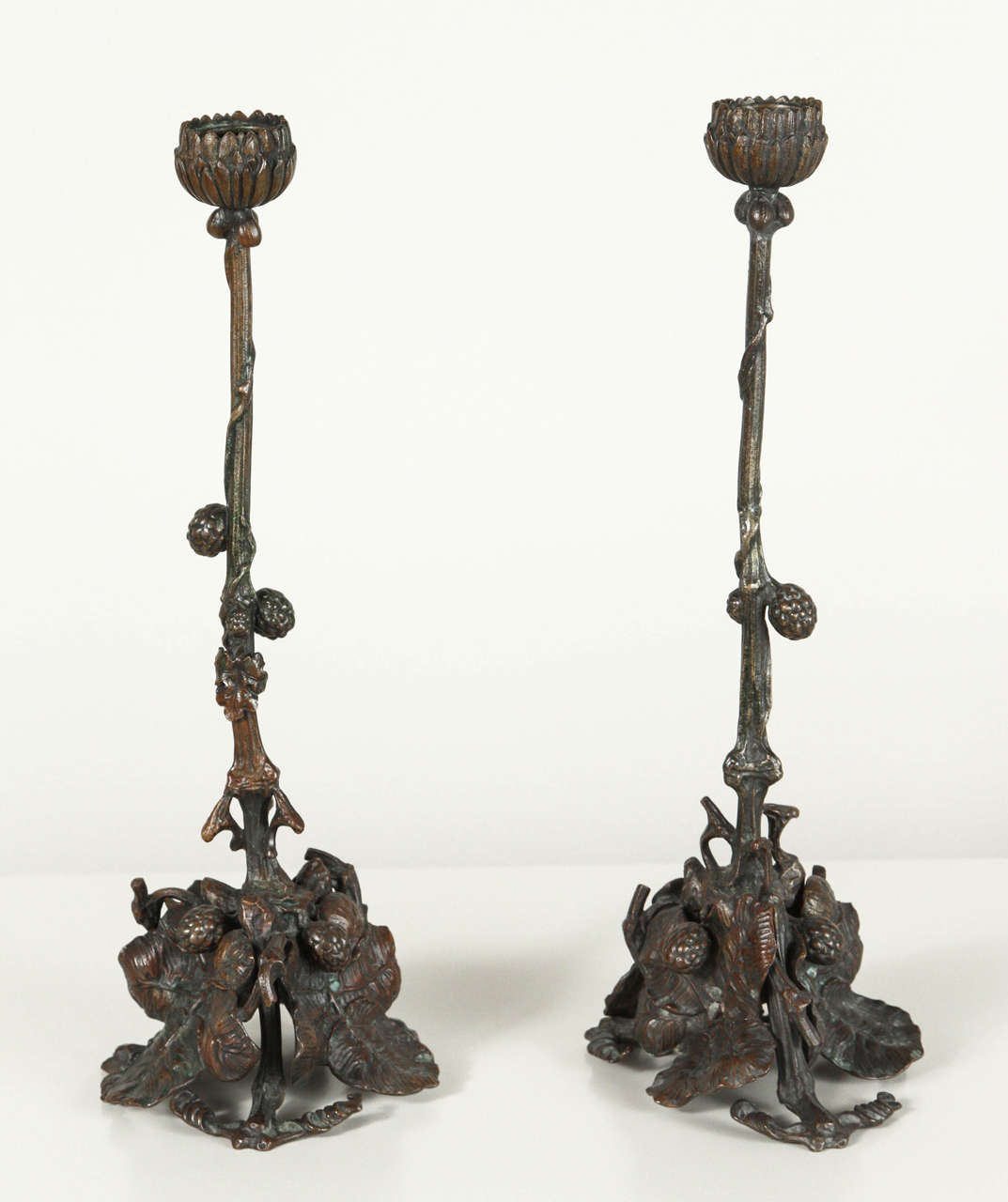 Arts and Crafts naturalist-style intricately made pair bronze candlesticks with leaves and berries.
