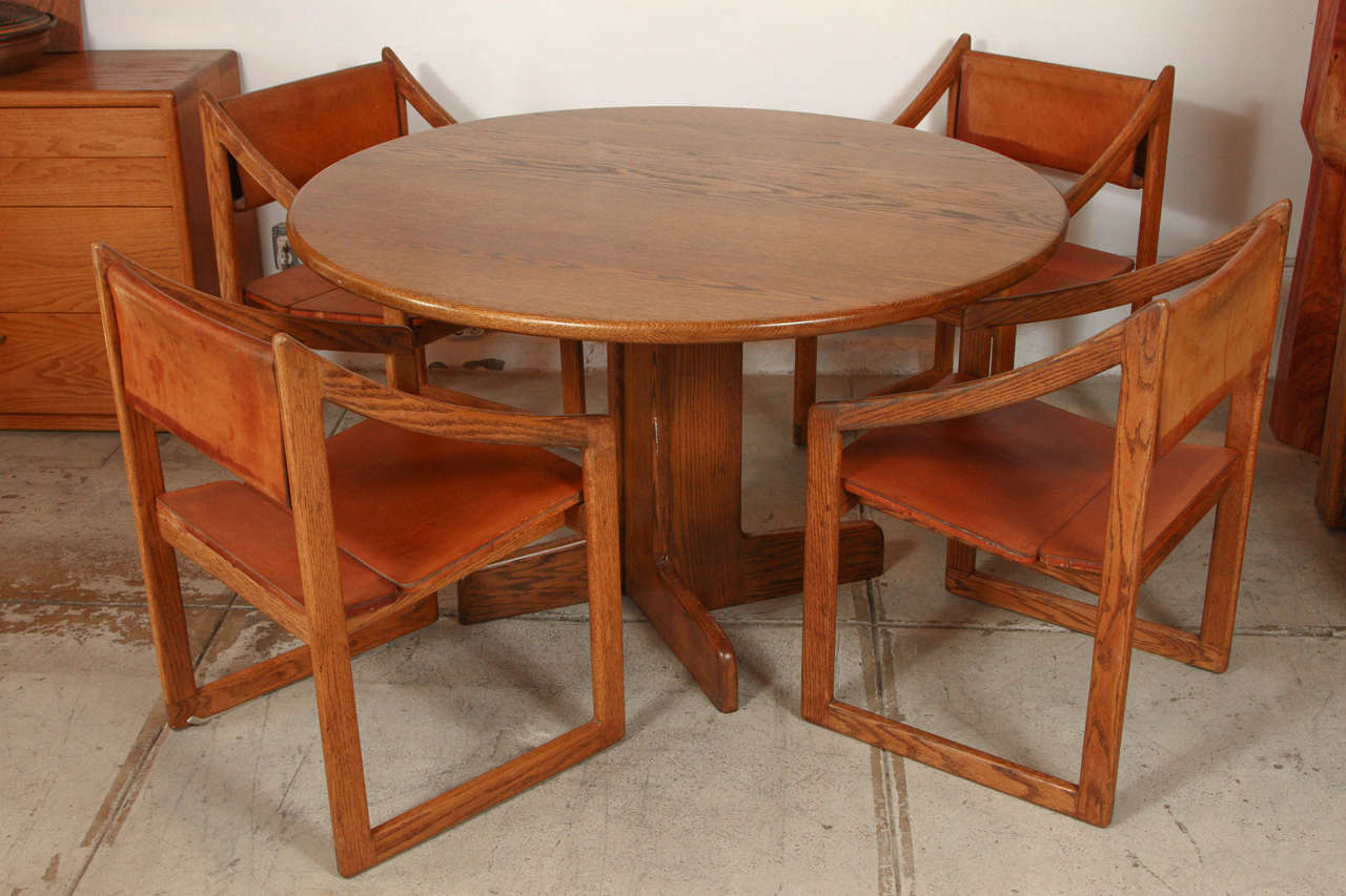 Round oak dining table with four oak and leather chairs by Gerald McCabe, circa 1970s.