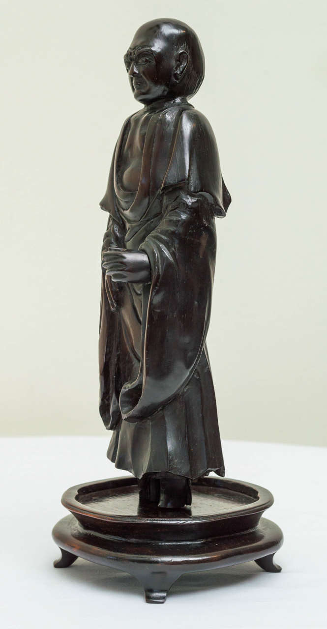 Early 18th century Chinese Qing period carved Lohan figure in draped robes. Very finely carved heavy dark rosewood. The aged surface patina with tight grain and figure with checked shrinkage and craquelure surface. Detailed carved hair and eyebrows