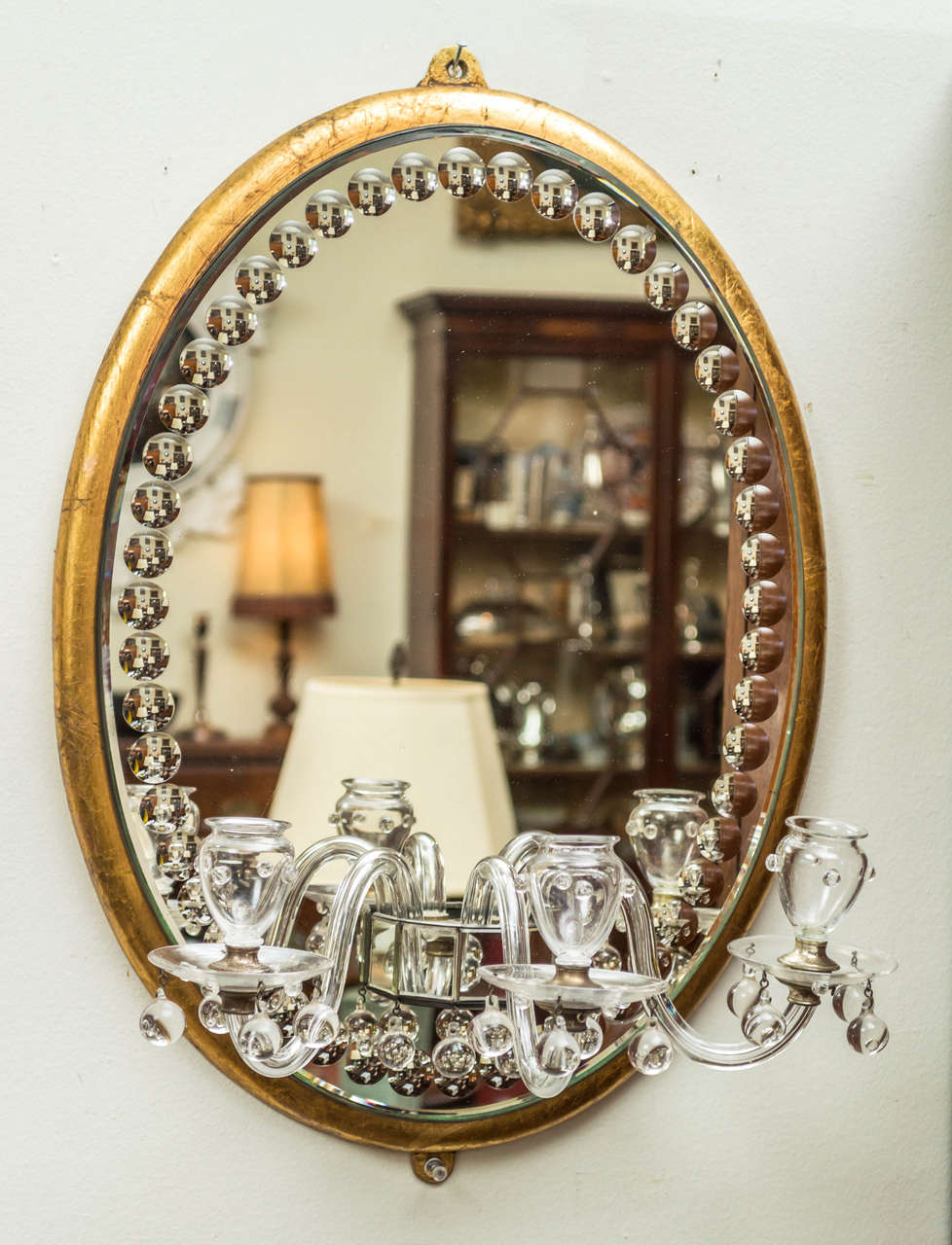 Mid-20th century oval girandole mirror fitted with three candle arms. Originally had five candle arms. The oval mirror glass bordered by thumb print cuts and framed in giltwood.