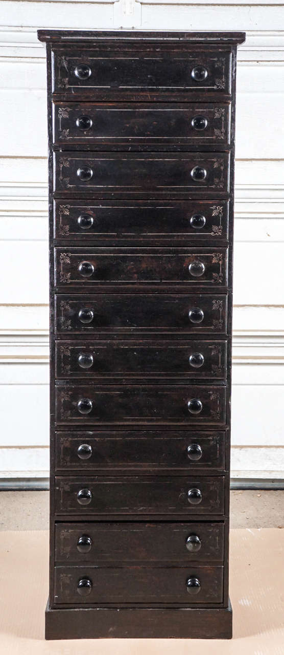 English painted pine eleven-drawer tall chest. Small pull-out shelf above the
fourth drawer from the bottom drawer is double depth. Gold scroll
decoration on all the drawer faces. Useful piece with all the drawers.
