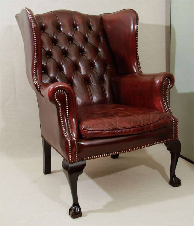 Georgian-Style Gentleman's Library Wing Chair in Burgundy Tufted Leather with Down Cushion, Brass Nail Head Detailing Raised on Mahogany Cabriole Legs with Ball and Claw Feet.  England, Late 19th/Early 20th Century.<br />
<br />
31 inches wide x