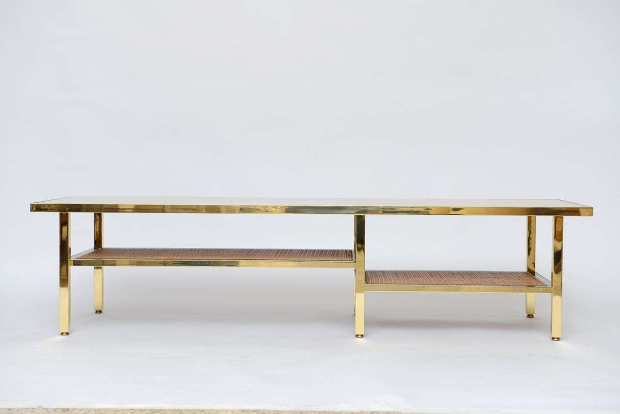 A sophisticated combination of materials give an elegant richness to this simple, clean-lined coffee table by Harvey Probber. Solid brass frame with travertine top and rattan shelves.