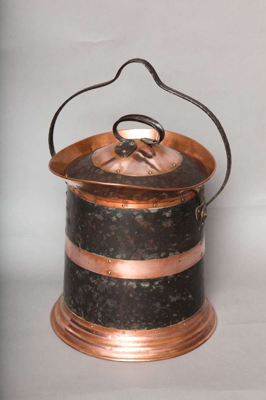 Arts & Crafts period handsome copper and iron hand riveted and hammered coal bucket having a stepped base, copper waist, nicely forged handles, wide copper spout and two-tone lid.

Firewood, kindling, log holder.
