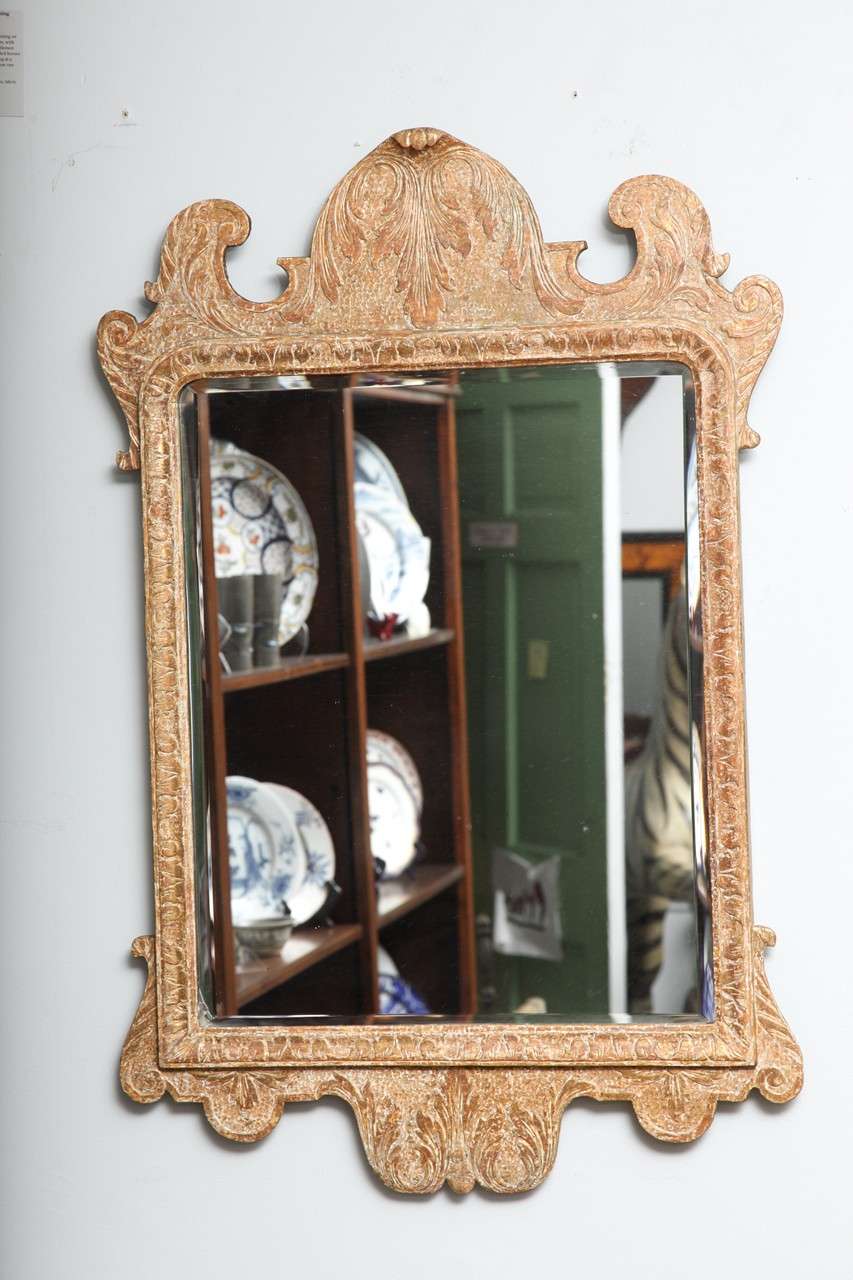 English or Irish George I period carved and gilt gesso mirror, the crest having foliate and strap work design, the leaf carved border molding surrounding beveled mirror plate, the surrounding frame similarly decorated, retaining much original