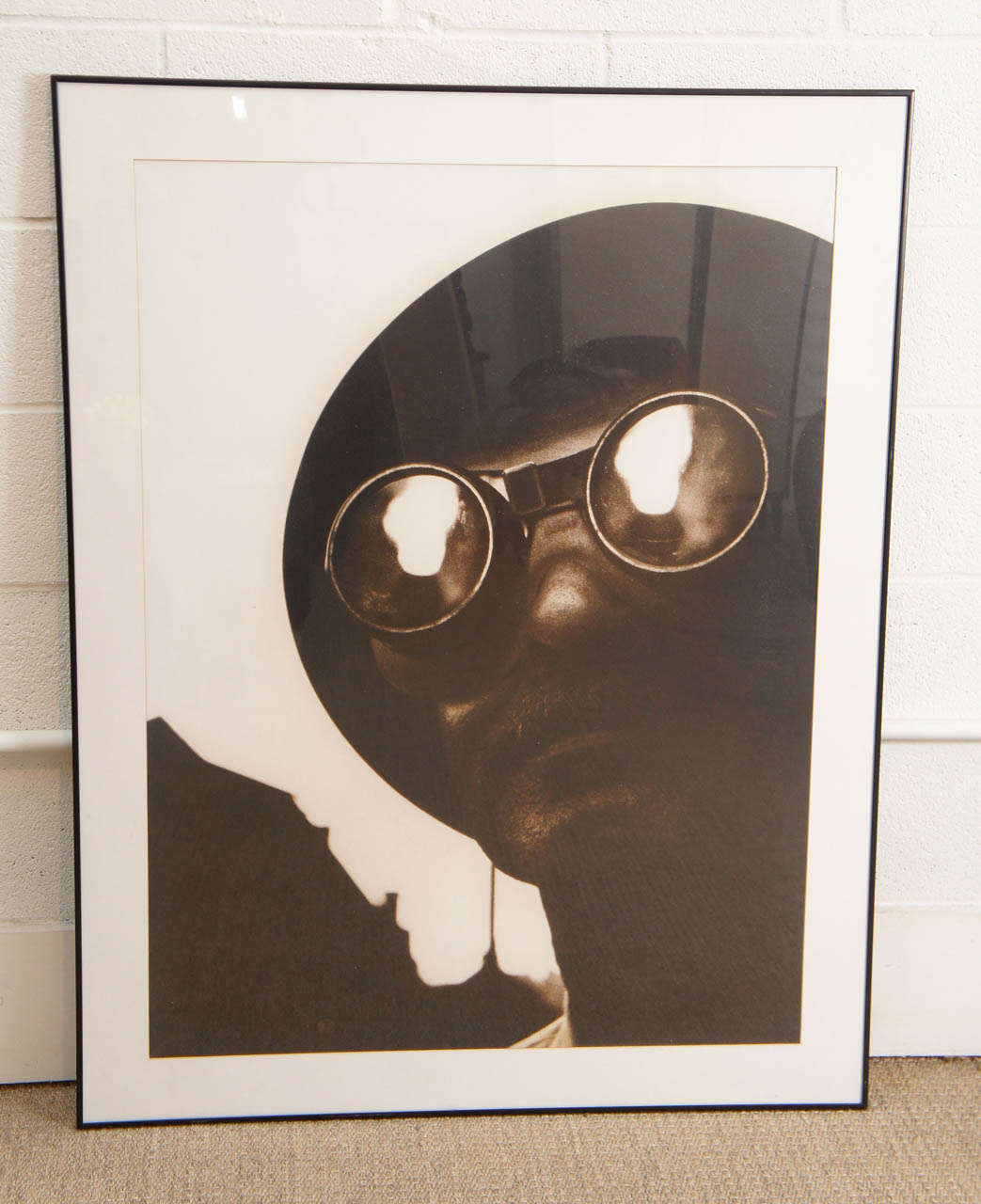 This is an offset print of an image of a man wearing goggles with a reflection of flames. The sepia toned image makes a bold and graphic statement.