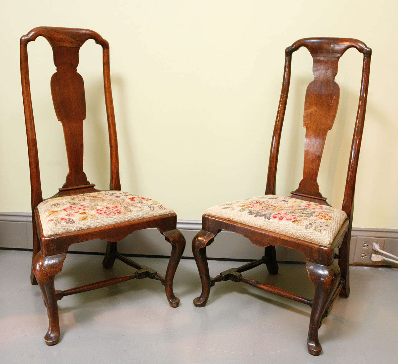 A Pair of English Queen Anne low hearthside chairs, mid 18th c. In walnut with needlework seats.  Very gracious proportions, incorporating cabriole legs, pad feet and vase-form back splat.