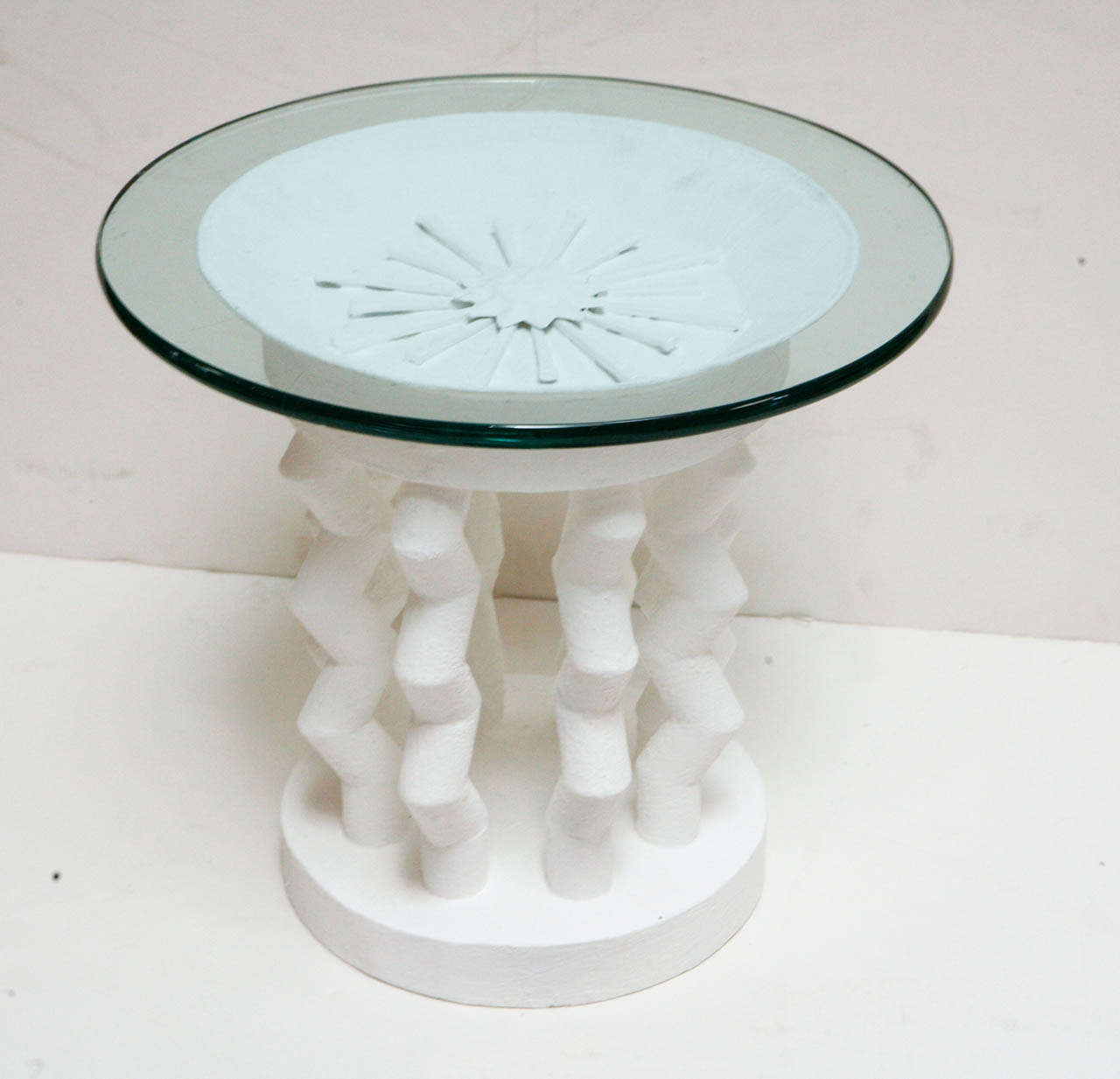 Round White plaster side table with geometric shaped base with intricate sunburst detail on top.  Metal frame coated in a white plaster.