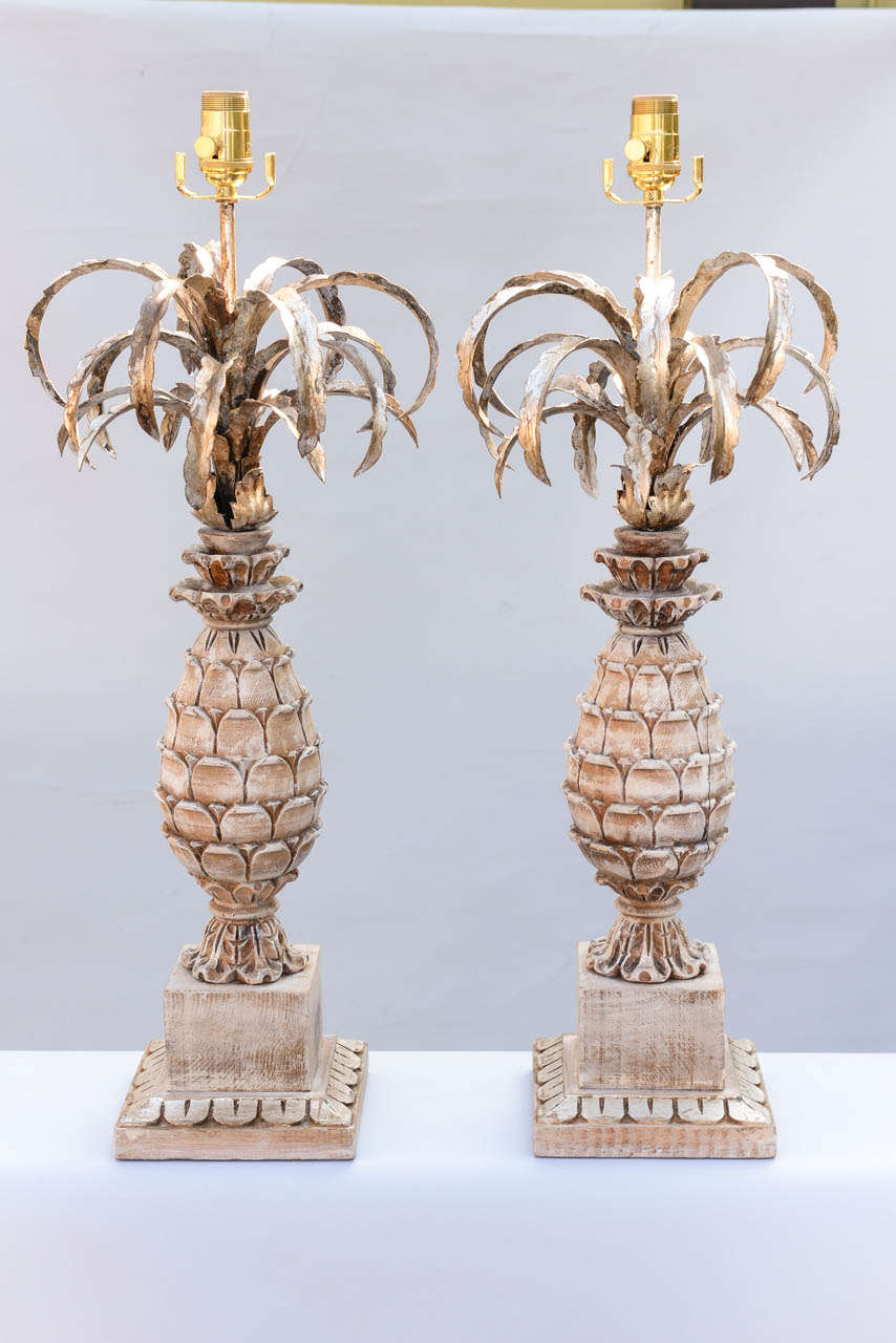 Pair of pineapple lamps, each having silvergilt iron leaves above a carved pickled wood pineapple, raised on square wood base.