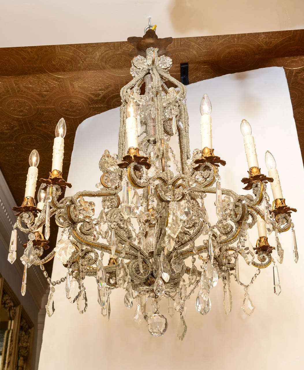 Chandelier, having a frame of gilt iron, entirely covered in macaroni crystal beads; its knopped, glass-sheathed center column surmounted by crown pediment finished with flower-form drops, its six scrolling candlearms split into doubles, holding