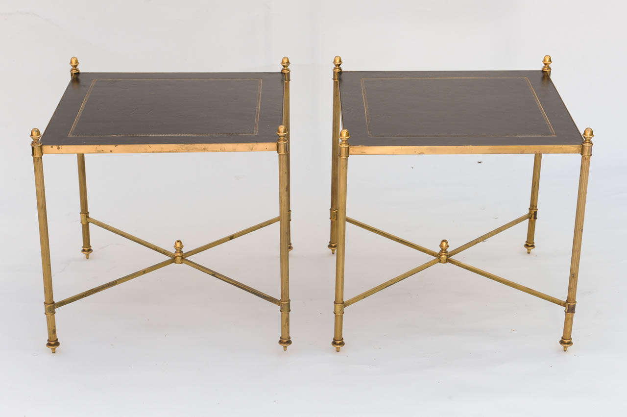 Pair of tables, by Maison Jansen, of dore bronze, each having black embossed leather top raised on round fluted legs surmounted by acorns and connected by X-stretcher.