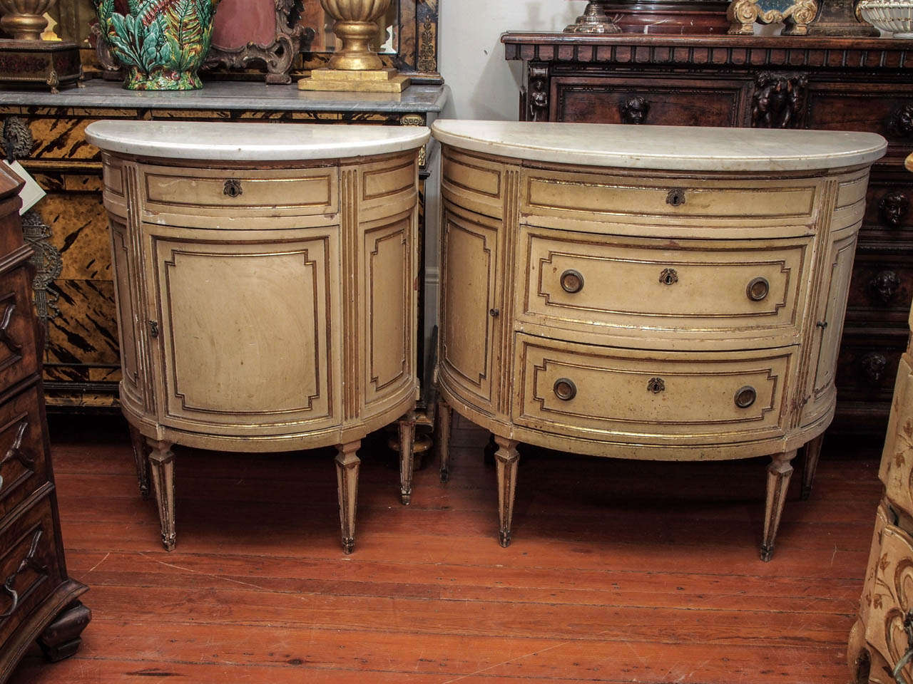 Suite of two Italian Luigi XVI Painted and Parcel gilt Demi Lune Cabinets , one with three drawers and to doors and one with one drawer and one door. both with marble tops. Size of the smaller one is 25.5 inches wide x 13.75 inches deep x 31.75