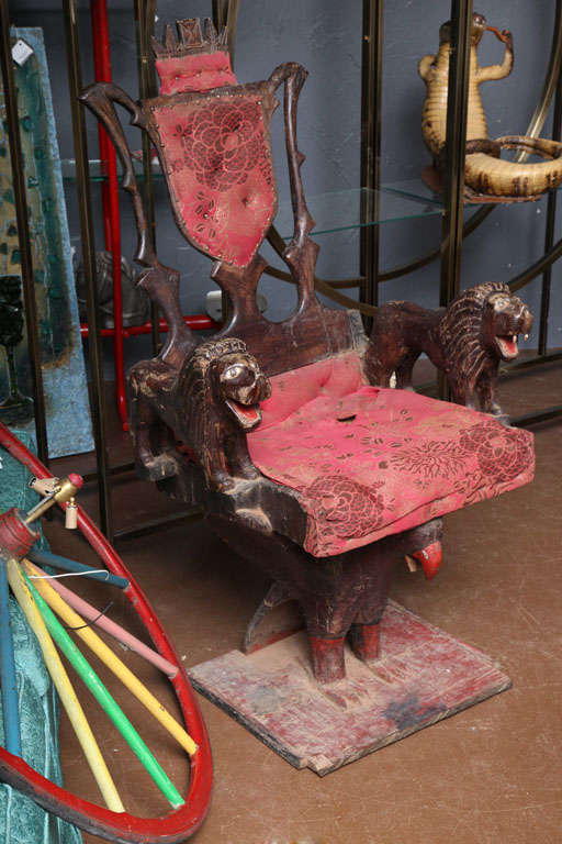 Most unusual ceremonial folk art chair. Eagle base is carved from one single piece of wood, with a standing lion on each wing.The upholstered back folds down onto the seat. Origin unknown.