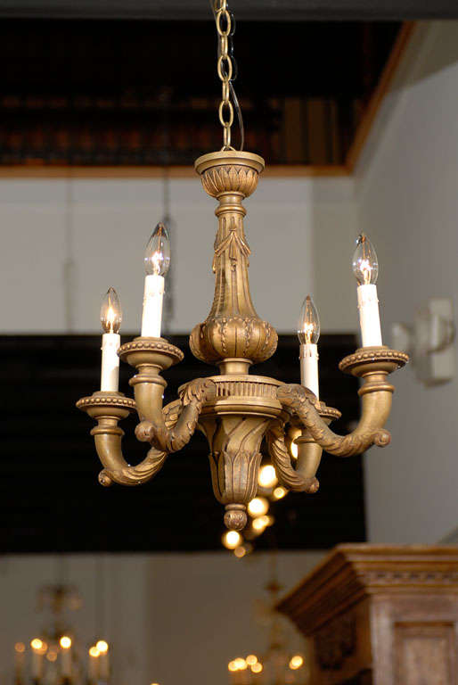 A French turn of the century four-light giltwood chandelier with carved central column and scrolled arms. Born at the turn of the 19th-20th century, this French chandelier features a central fluted column, adorned with delicately carved swags and