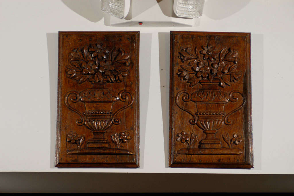 A pair of French period Louis XVI hand-carved wooden panels with urns and bouquets from the late 18th century. This pair of French wooden architectural panels was born in France during the short reign of King Louis XVI. Each panel features a