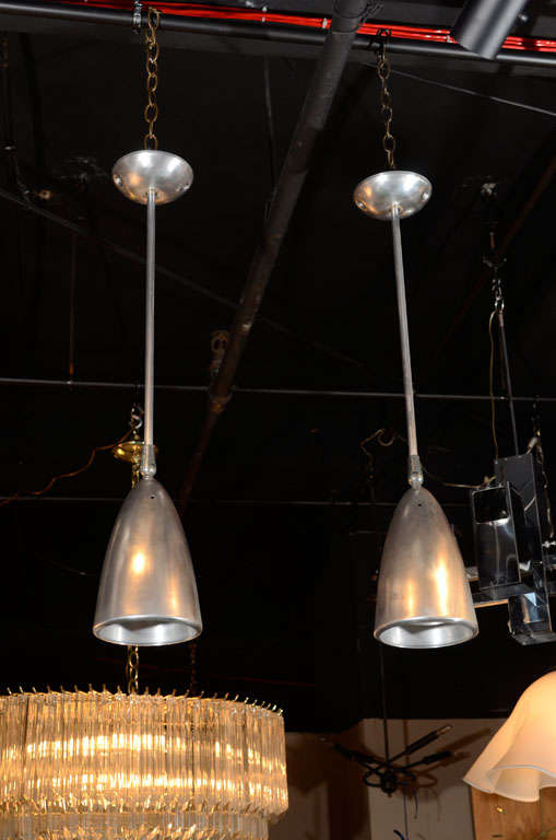 Pair of brushed stainless steel pendant light fixtures.  USA, circa 1950.  Adjustable shade; canopy included.  Possibly made by Litecraft or Lightolier.
