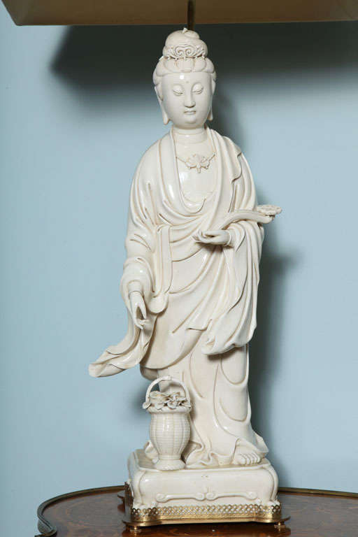 A pair of Chinese standing Blanc de Chine Kwan yin, one is in the sea and the other with a flower basket at her feet.
