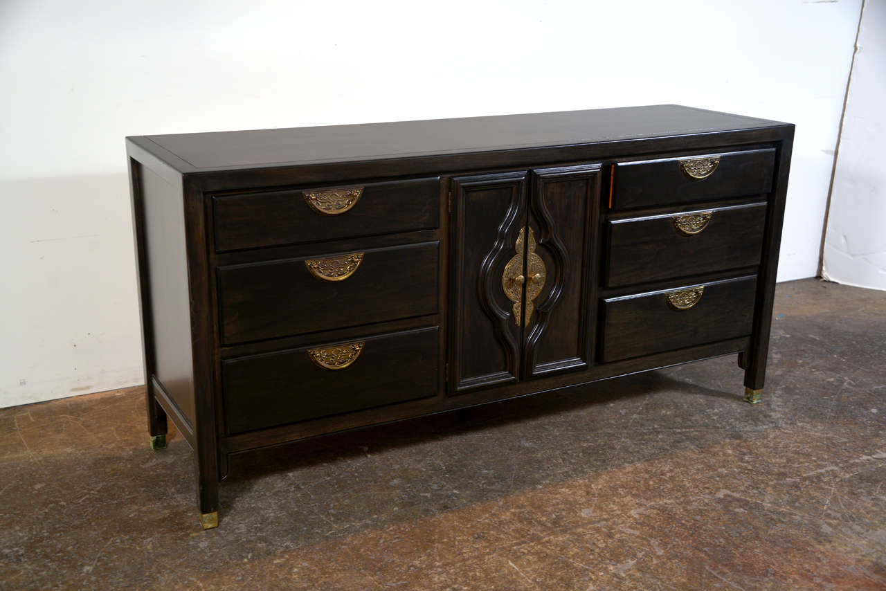 Beautiful ebonized dresser with 9 drawer, three drawers on the right and left sides and three behind door panels in middle. Asian influenced brass hardware adds timeless elegance to this handsome piece.