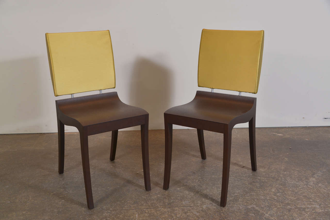 Set of six modern dining chairs with a wood base frame with curved seat give an illusion of being sculpted out of solid wood. Each chair is extended with metal tubing with an upholstered foam cushion backrest.