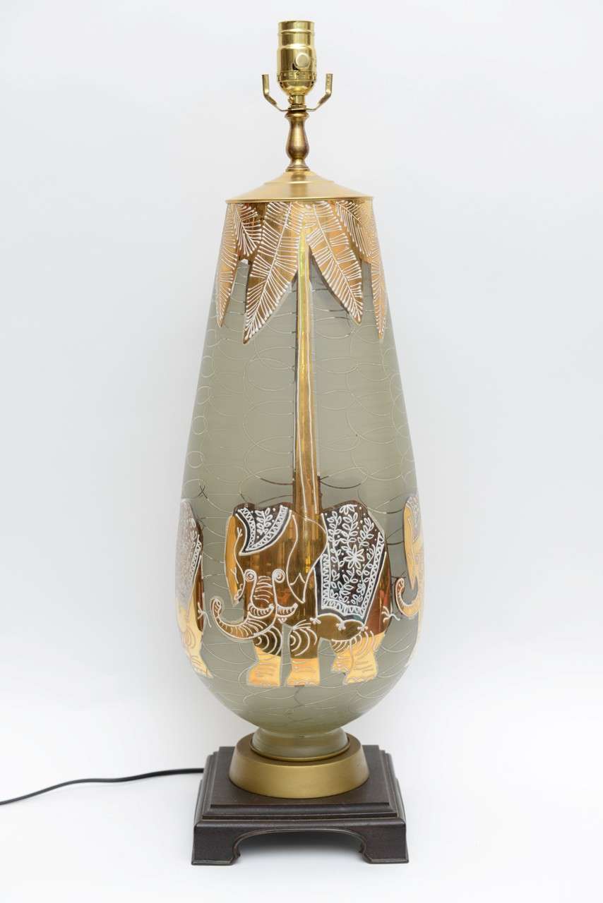 If not Waylande Gregory, certainly channeling his wonderfully elegant humor and playful style, this exquisite tall etched, gilt and enamelled teardrop shaped blown glass table lamp has four magical large gilt elephants around its body with palm tree