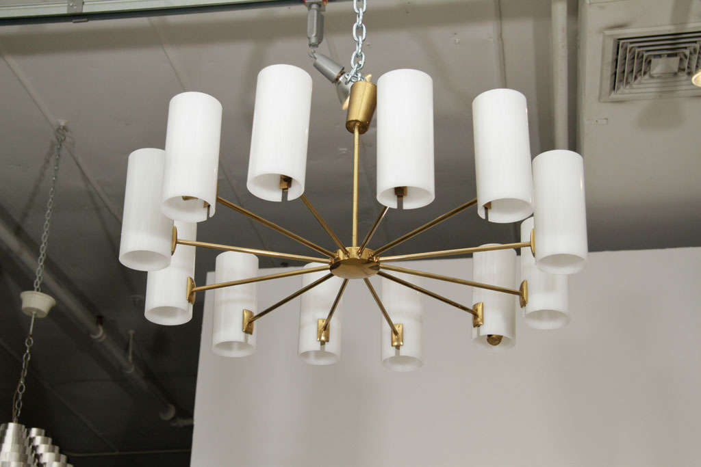 Twelve-arm gold chandelier with white plexi cylinder shades.