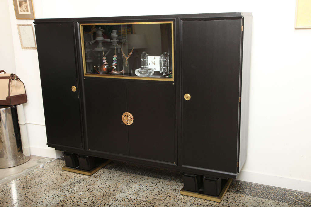 Un fantastico mobile in legno ebanizzato con un ampio spazio di archiviazione con due grandi porte laterali che si aprono su scaffali, un magazzino centrale aperto e finestre scorrevoli in vetro per l'esposizione.

Hardware/medaglione progettato