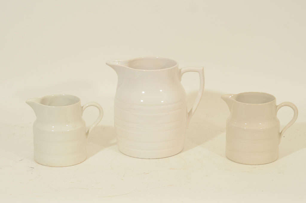 Collection of Three Cream-Colored Dairy Jugs in Varying Sizes with the Largest Stamped, 