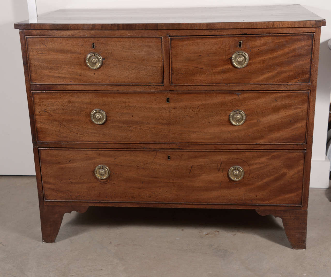 18th century English mahogany chest with four drawers on bracket feet. Simple straight lines and beautiful patina. Brass circular pulls.