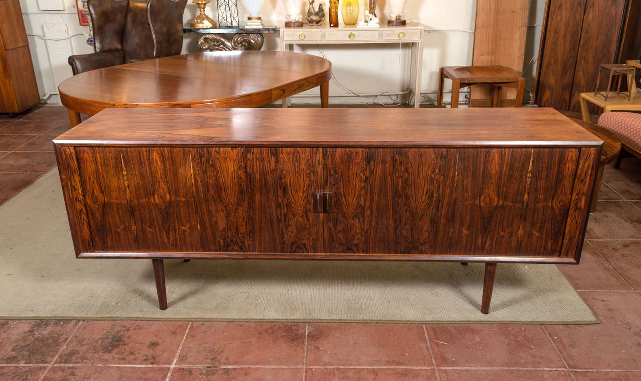 A very large rosewood credenza, Denmark, circa 1960s. It's attributed to Ib Kofod-Larsen and Omann Jun. Has a wonderful dark grain, tambour doors, three ajustable shelves and four green felt lined drawers.