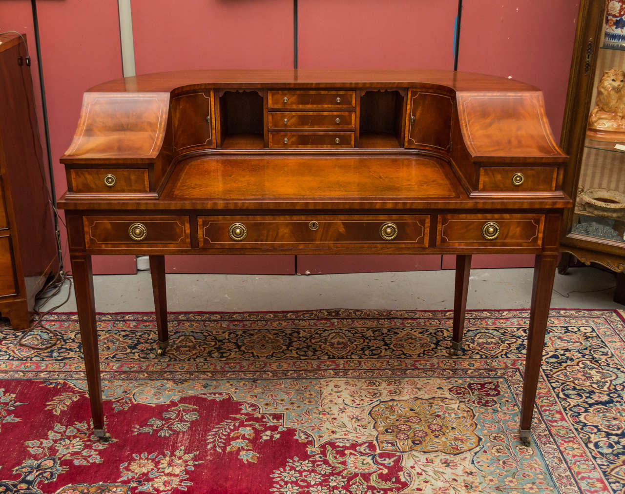 A Carlton House writing desk, Mahogang with string inlay and rounded molded back, showing drawers and cupboards above an original tooled writing surface, and tapering square legs with Brass caps, and castors. Recently French polished.  
A Carlton