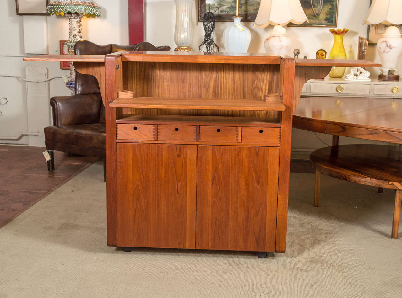It's a large Teak bar with tons of storage space for all your favorites, at the same time very compact for the amount of storage it does have. Top slides back, and folds down, showing where the bottles would be stored and gives you a work area for