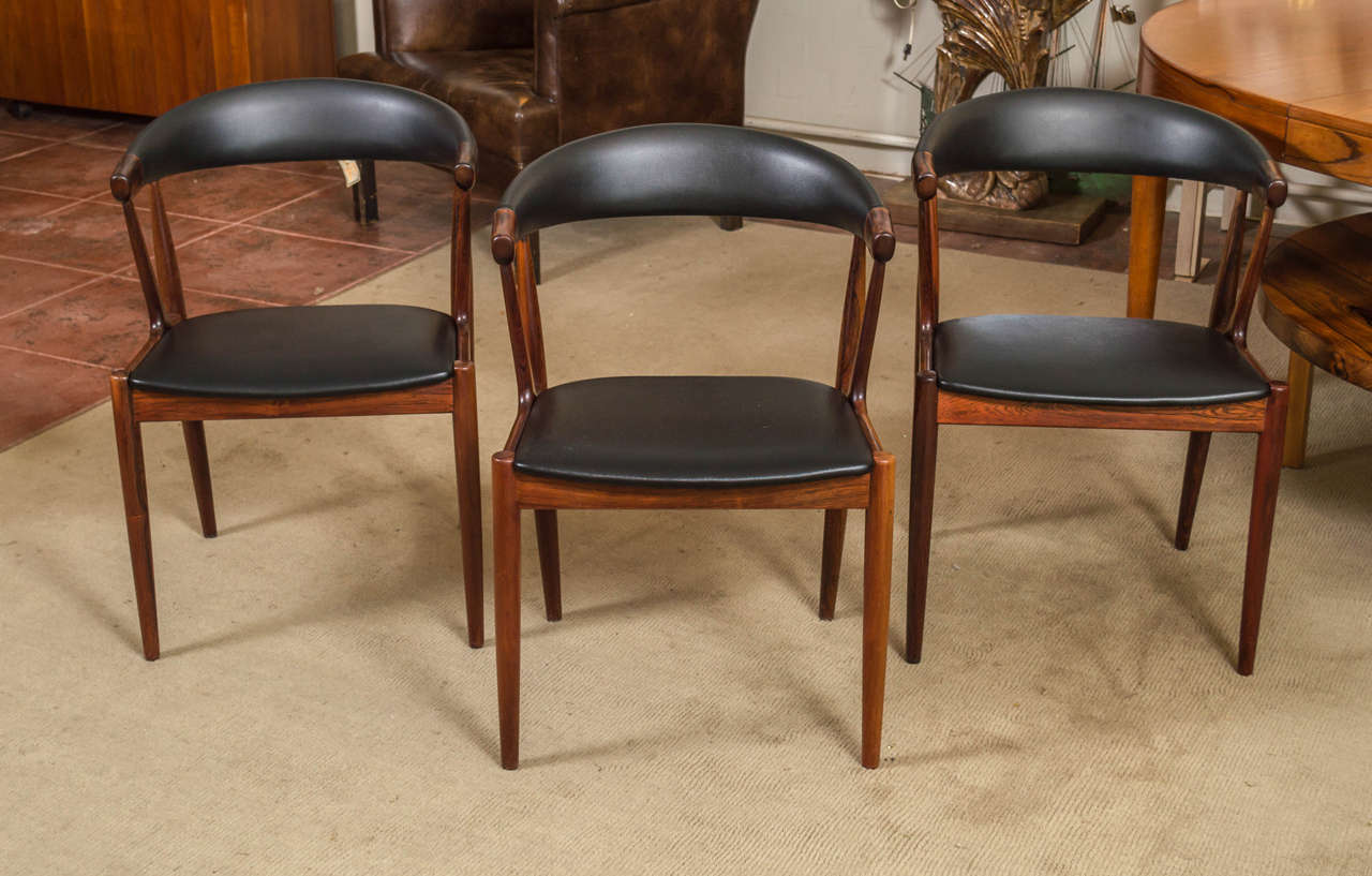 Set of six Danish dining chairs, designed by Johannes Andersen. Frames are Rosewood, upholstery is black vinyl. These would make a very nice addition to your modern home.