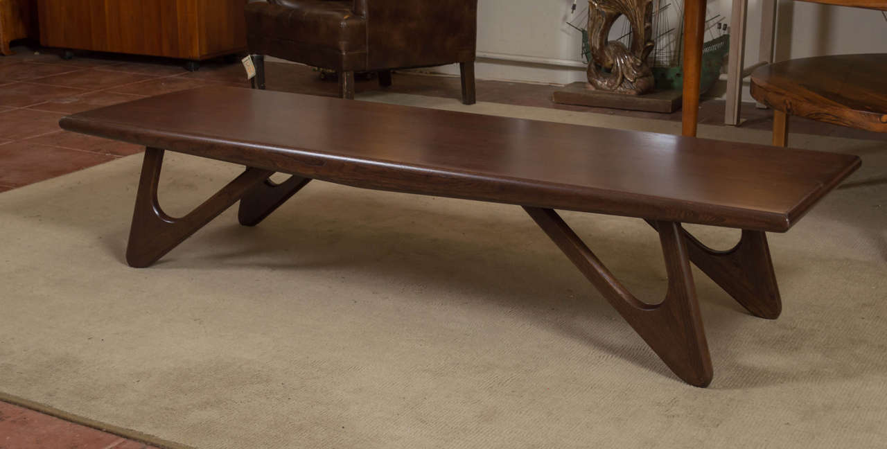 Great-looking mid century Walnut coffee table, with a great set of legs. Designer is unknown, but reminds you of the fun space age/fluid designs of the 50s. It's a well made table.