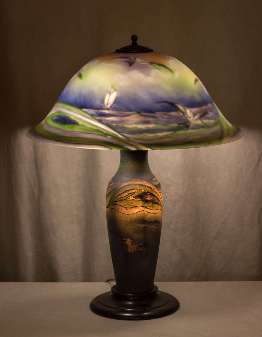 This has always been considered one of this company's more exotic and artistic lamps. Pictures do not get the full Scope of the color and presence this lamp offers. The shade is artist signed H. Fisher and there is a small paper remnant of the