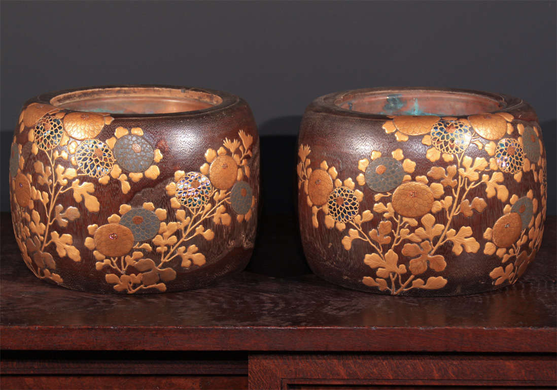 A pair of Japanese te-bachi (hand warmers). Constructed of kiri (Paulownia) wood, the surfaces finely carved and decorated with elaborate floral motifs executed in gold maki-e lacquer and inset with pewter and abalone shell. With fitted copper