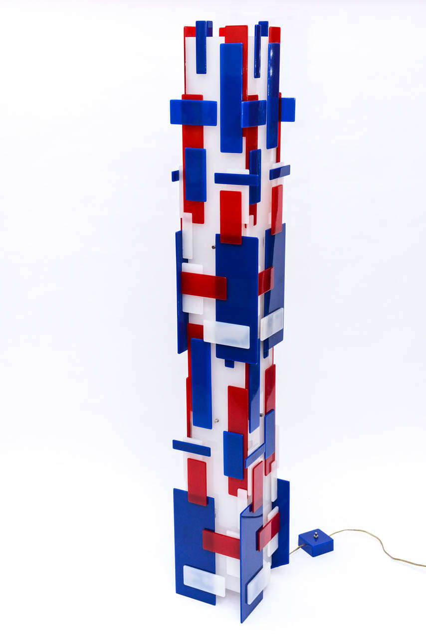 This amazing, unique scuptural floor lamp is beautifuly made and you will have all your guests talking about it.  Varying sizes of acrylic squares and rectangles in red, white and blue are affixed around a white central column.  This irresistible