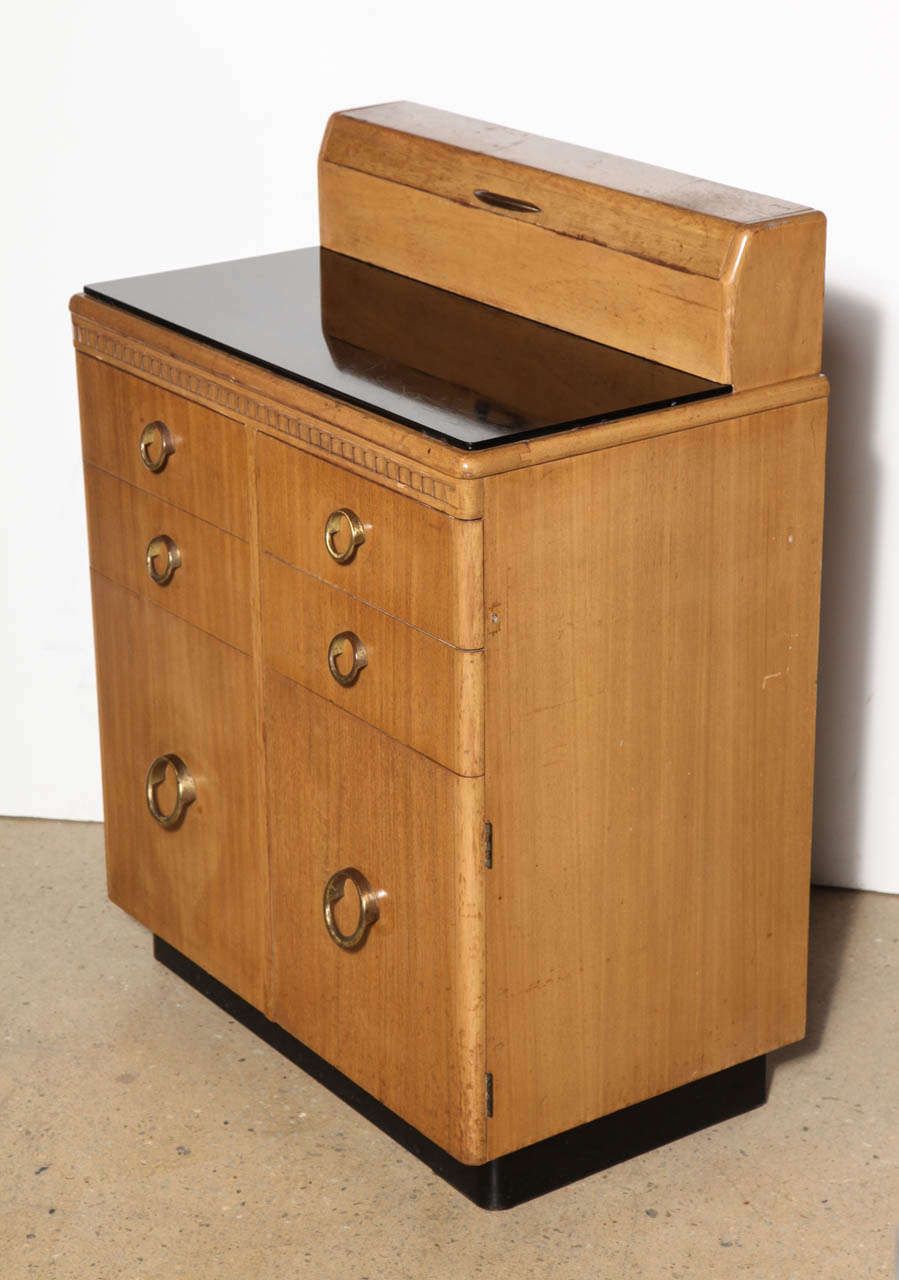 Compact 1940's multi use bleached Mahogany medical Cabinet with round Brass pulls. Complete with 4 metal lined drawers, 2 lower cabinets and top pull up storage area.  Black base with reflective Black vitrolite glass Display, Work or Serving surface