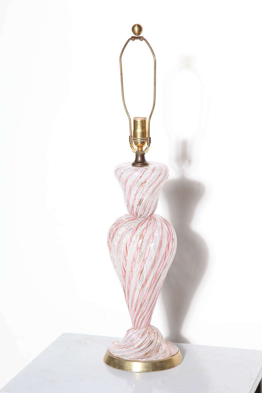 shapely and translucent Hollywood Regency Murano hourglass Pink and White Filigrana Glass Lamp hand blown by Arileano Toso.  Pale Pink ribbon design with White lattice and Metallic highlights seated on round angled Brass base.  Perfect feminine