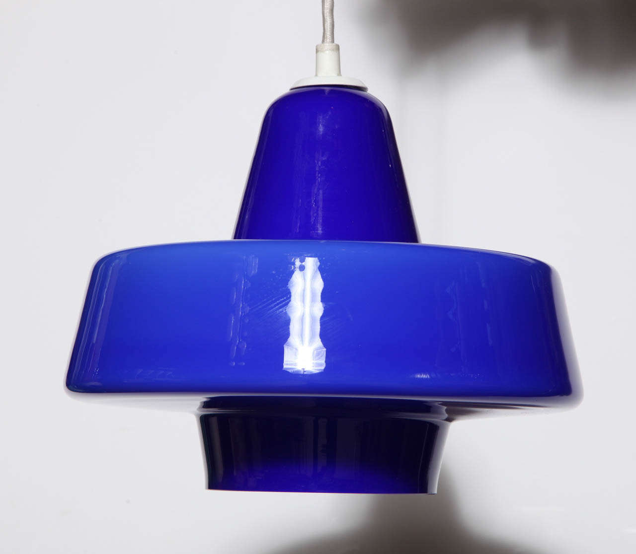 Danish Modern Adjustable Holmegaard Style Bright Cobalt Blue Glass Hanging Pendant. Featuring a modernist bell shape form with a brilliant vivid Blue glass exterior and White interior. With long, adjustable 5.5' white cord. 