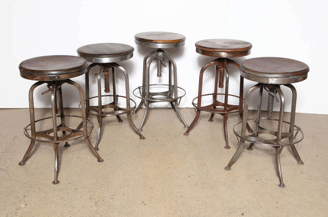 well matched set of 5 early 20th century adjustable riveted Steel and Wood Toledo Stools.  Adjustable height range from 27