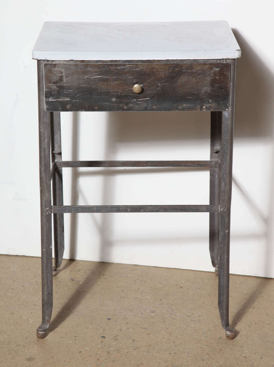 early 20th Century Night Stand in refinished Steel with White Enamel Top.  Complete with Steel Drawer, round Brass pull and wooden ball feet details.  Open base with supports for lower shelf.  Great multi use piece, 
perfect Bathroom, Kitchen or