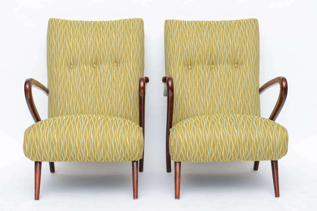 The upholstered seat and back with sculptural arms and round tapering legs.